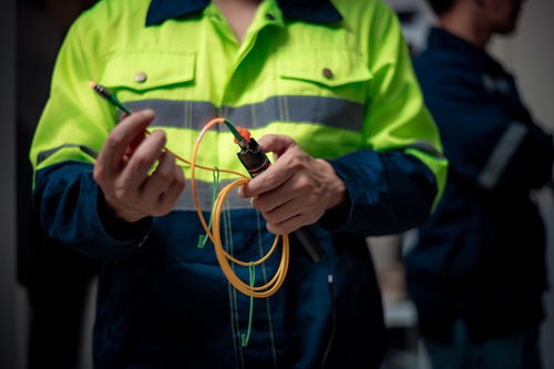 Technician in Thailand aligning optical fiber cables with a fusion splicer